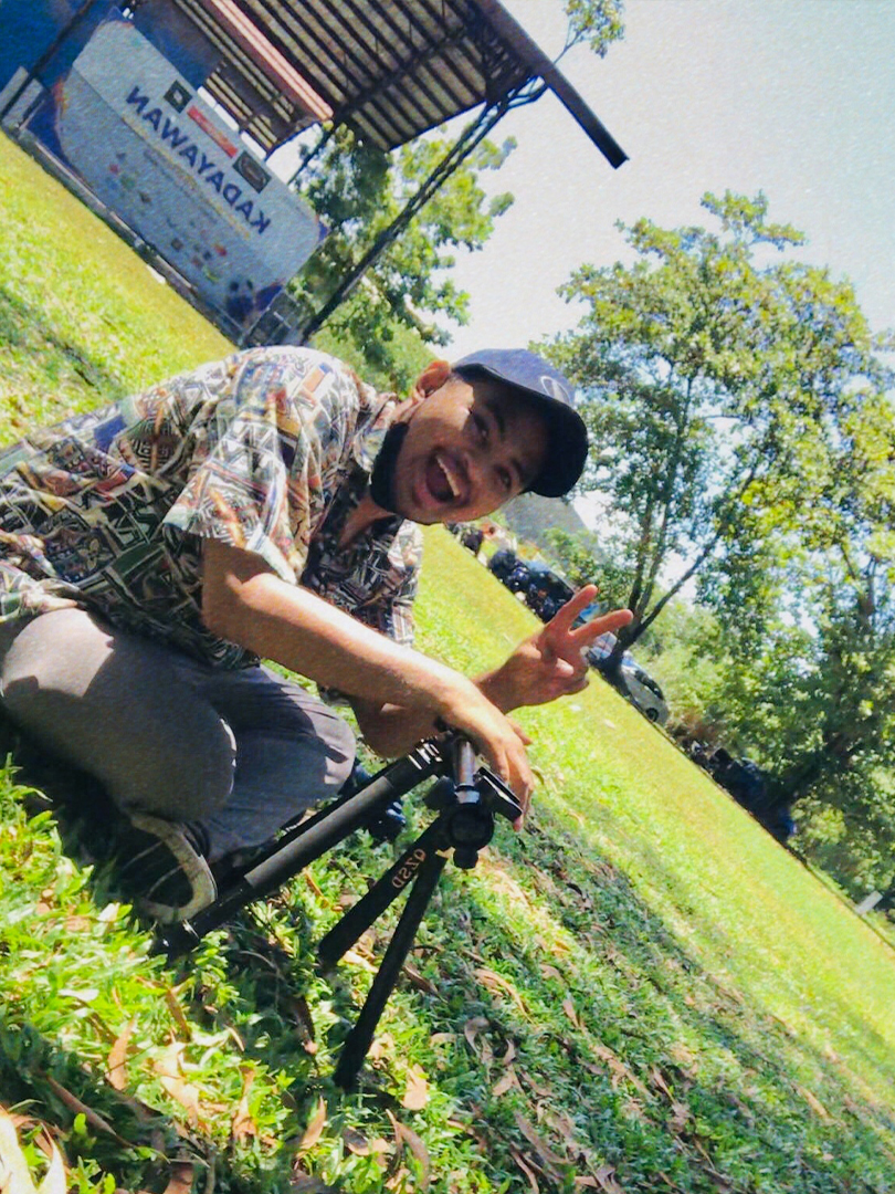 Director in grassy field posing for camera