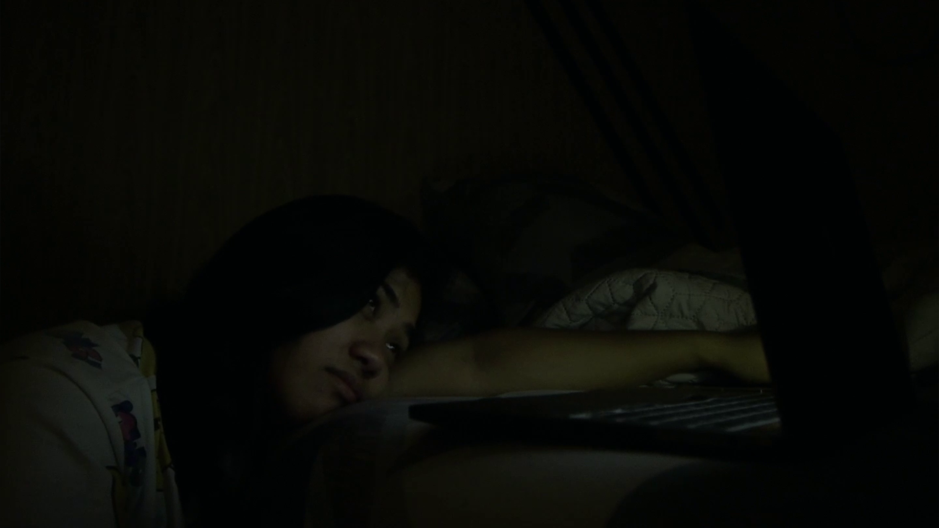June distressed in dark room, light of the laptop illuminating her face